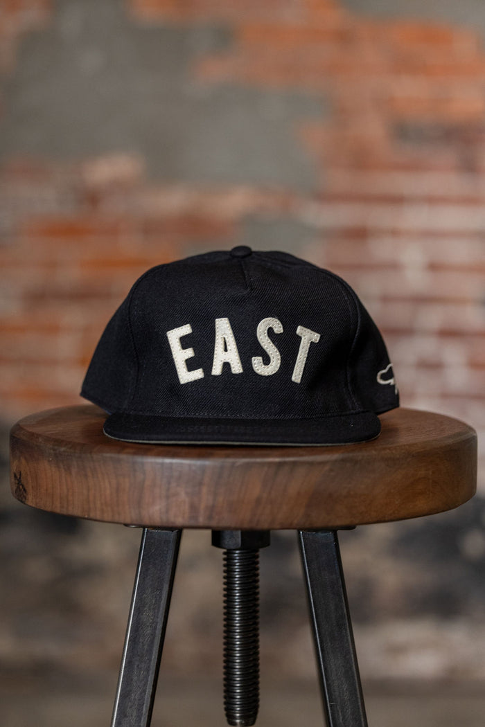Ampal Creative East - Snapback. on stool front profile