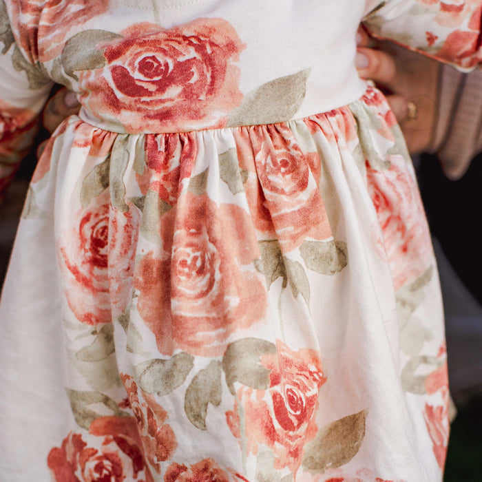 Cream rose-print tunic with gathered waist and flowing skirt; elastic cuffs