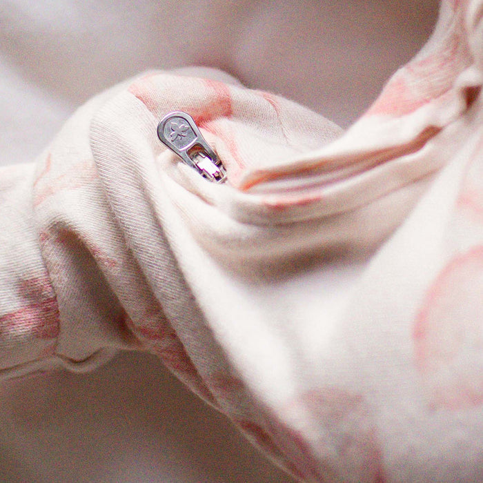Close-up of snap button on white romper fabric with pink ballet slipper print