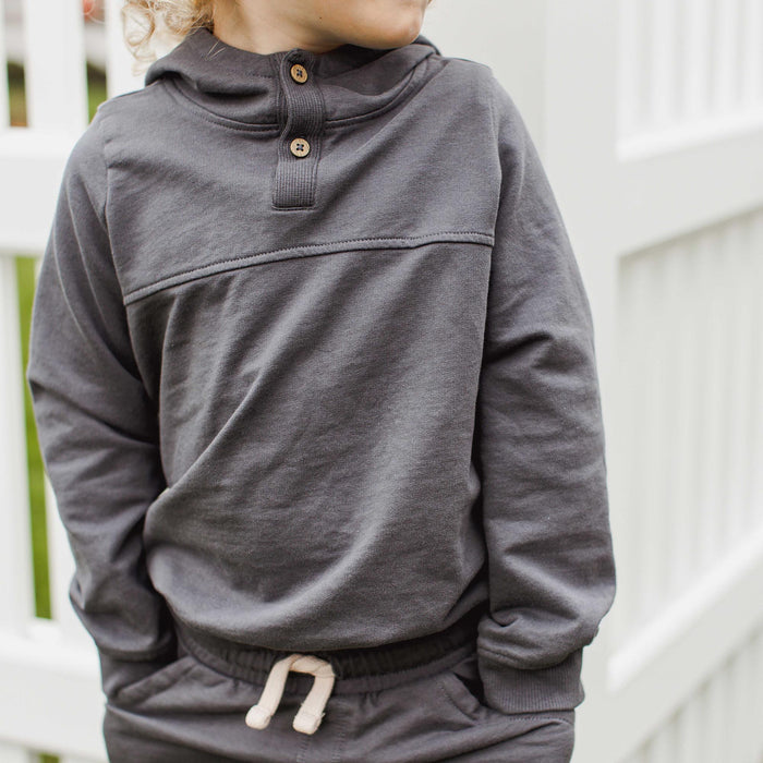 Dark gray organic cotton hoodie worn by child, half-button placket and hood