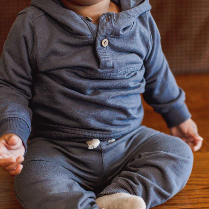 Dark gray organic cotton hoodie worn by child, ribbed cuffs and button placket