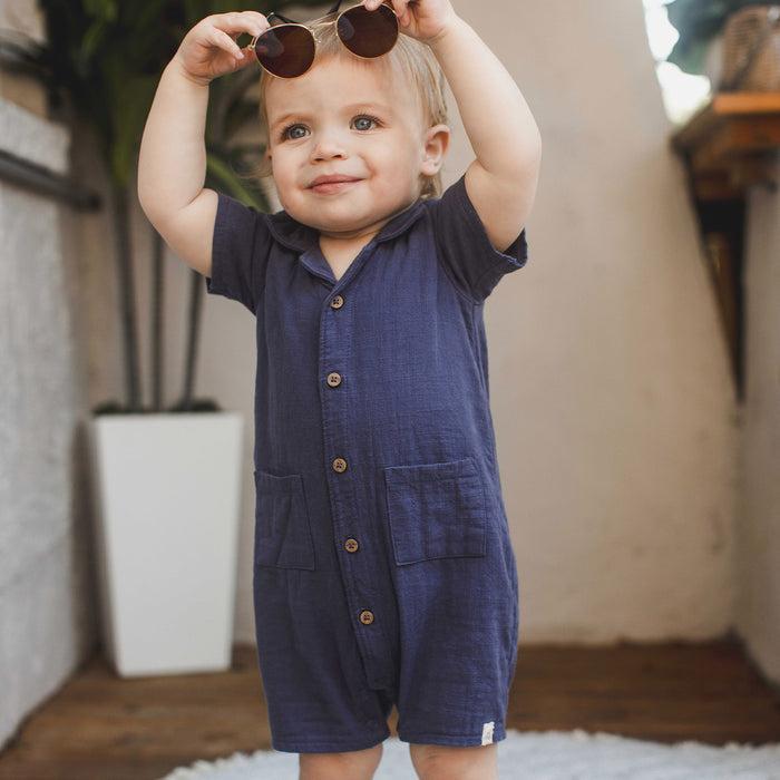 Navy checked gauze baby boy romper with front buttons and chest pockets, on child