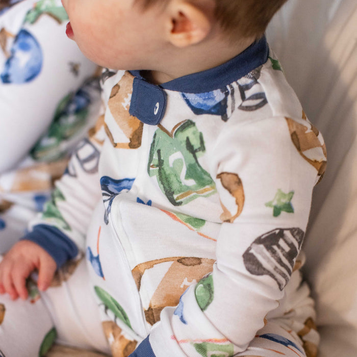 Close-up: football-pattern footed sleeper with navy snap collar and cuffs