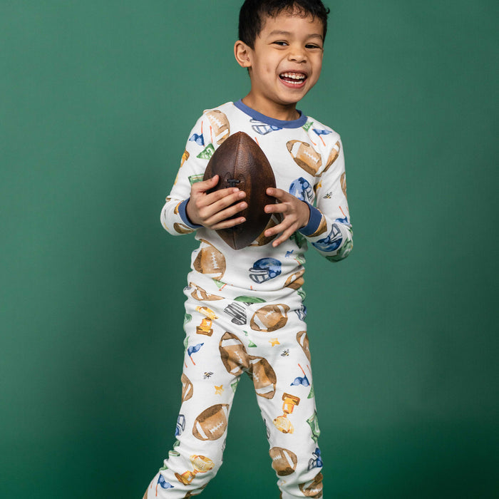 Kids football pajama set worn by child, white long-sleeve top and matching long pants