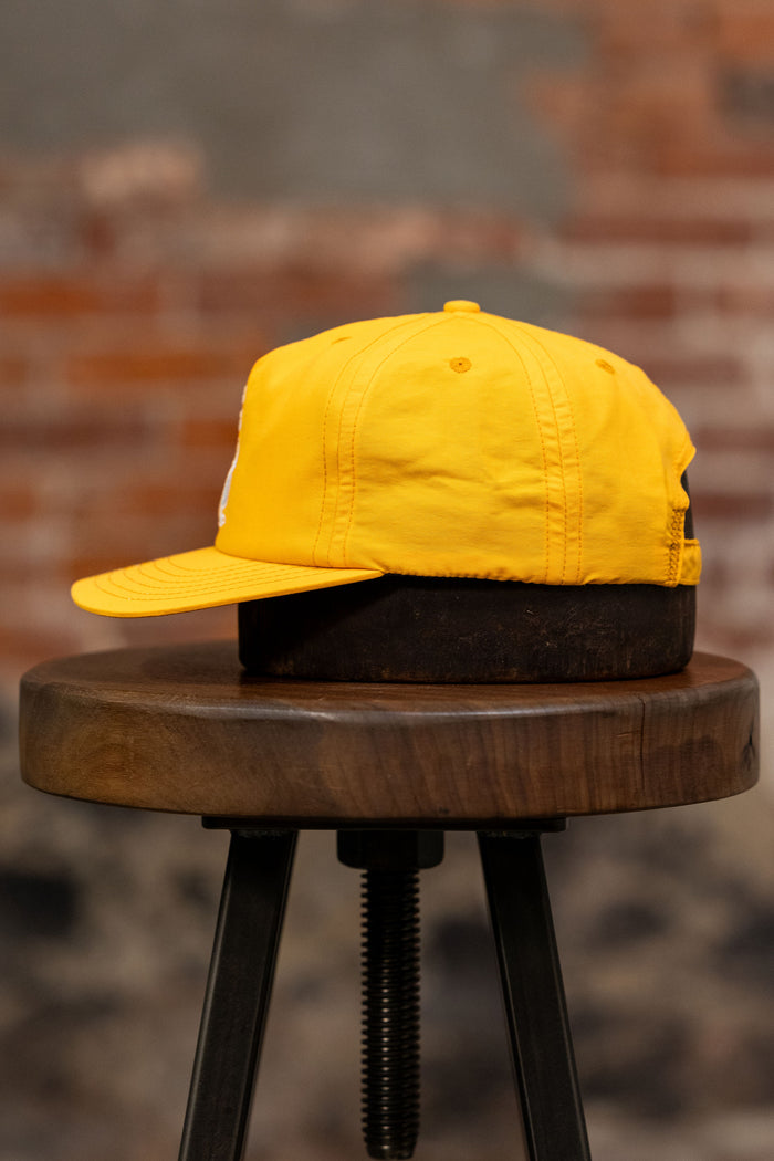 Franklin & Poe Surf Cap - Nylon Gold on stool, facing the side.