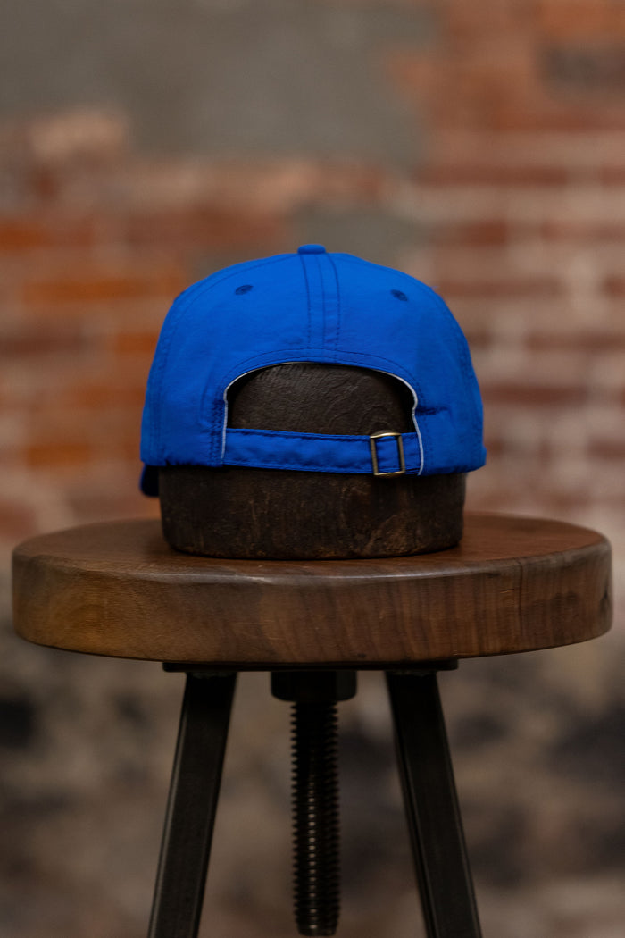 Franklin & Poe Surf Cap - Nylon Royal Blue on stool, facing away from the camera. Showing adjustable strap.