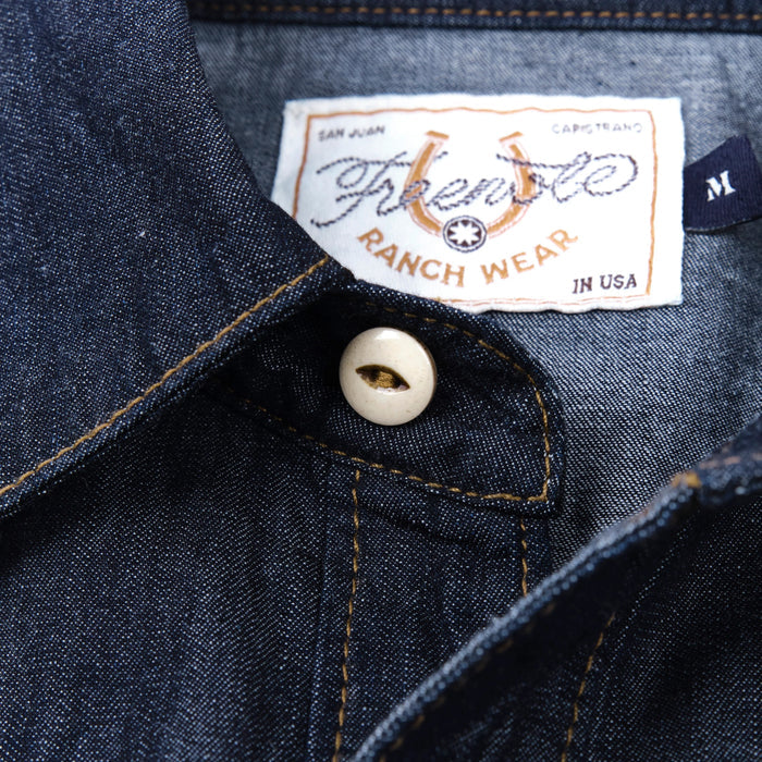 Dark indigo denim western-style short sleeve shirt with white snaps, close up top button of collar laying flat