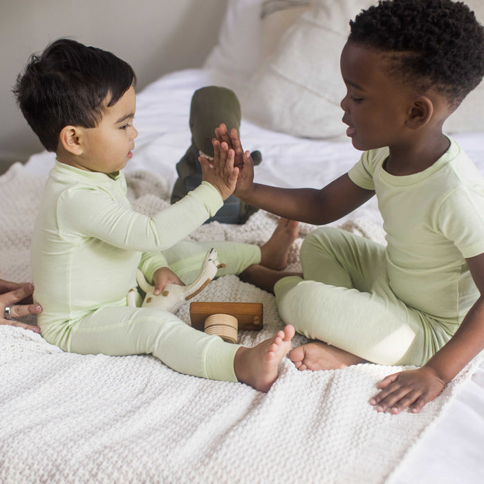 Sea green footless baby sleeper worn by baby, long sleeves and zip front
