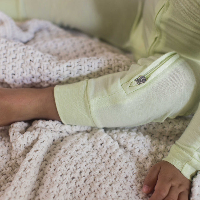 Sea green footless sleeper leg close-up with embroidered logo label