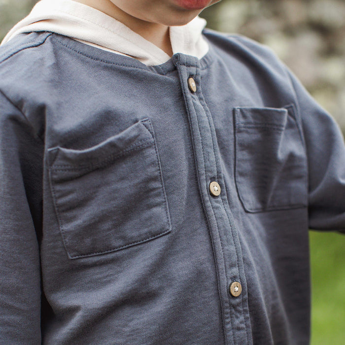Hooded button-down shirt with dark blue fabric, beige hood, and two chest pockets