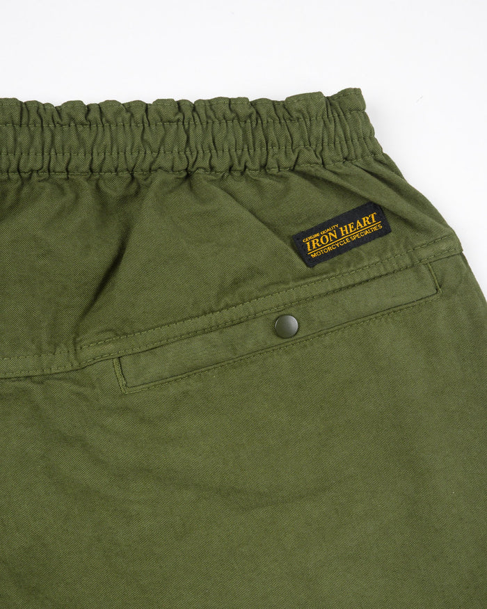 Olive mid length shorts back view laying flat closeup on snap pocket and black/yellow Iron Heart logo