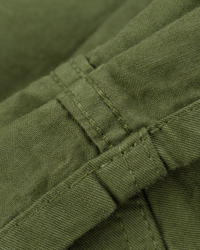 Olive mid length shorts laying flat closeup on stitching