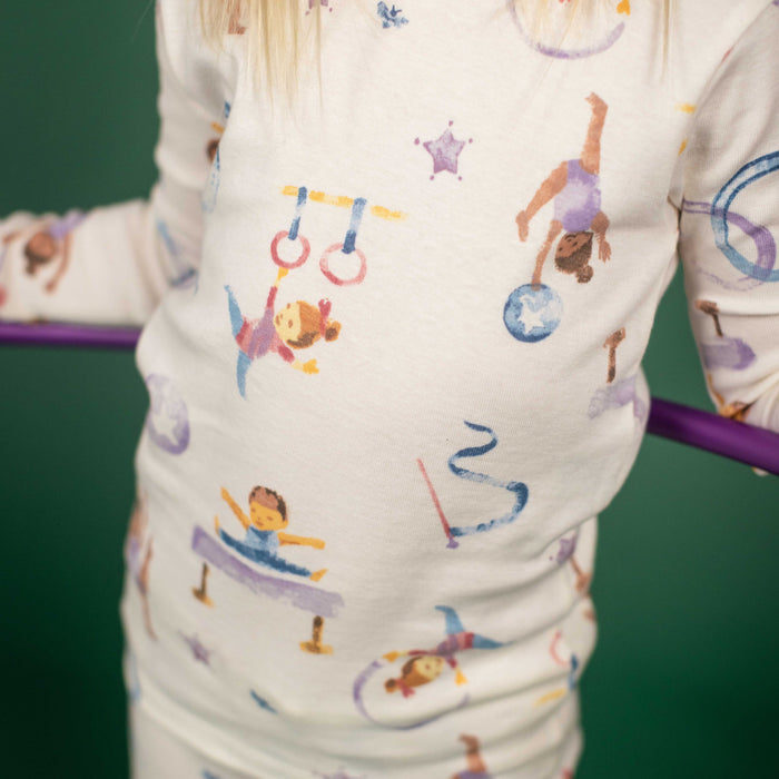 Cream pajama fabric close-up with colorful gymnastics figures and equipment print