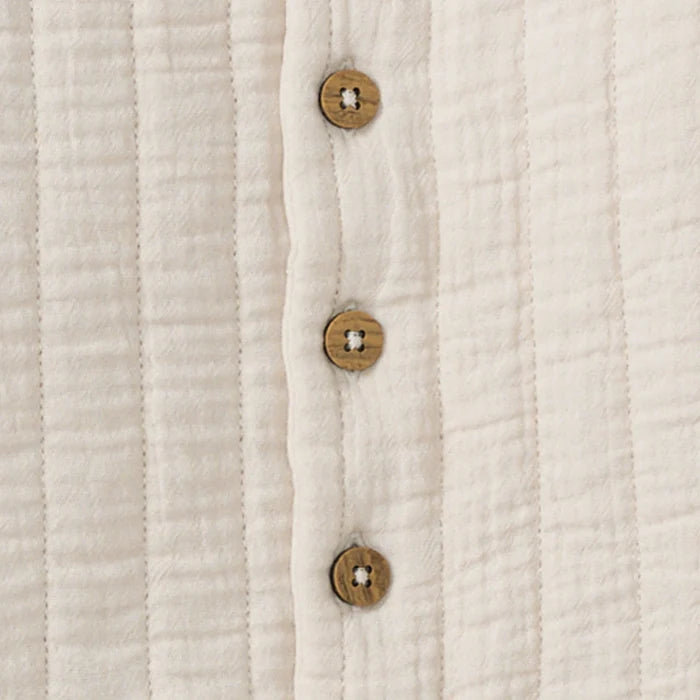 Close-up of off-white quilted jacket with three wood-look buttons on placket