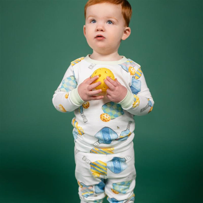 Toddler in white long-sleeve pajamas with blue and yellow pickleball print and matching pants