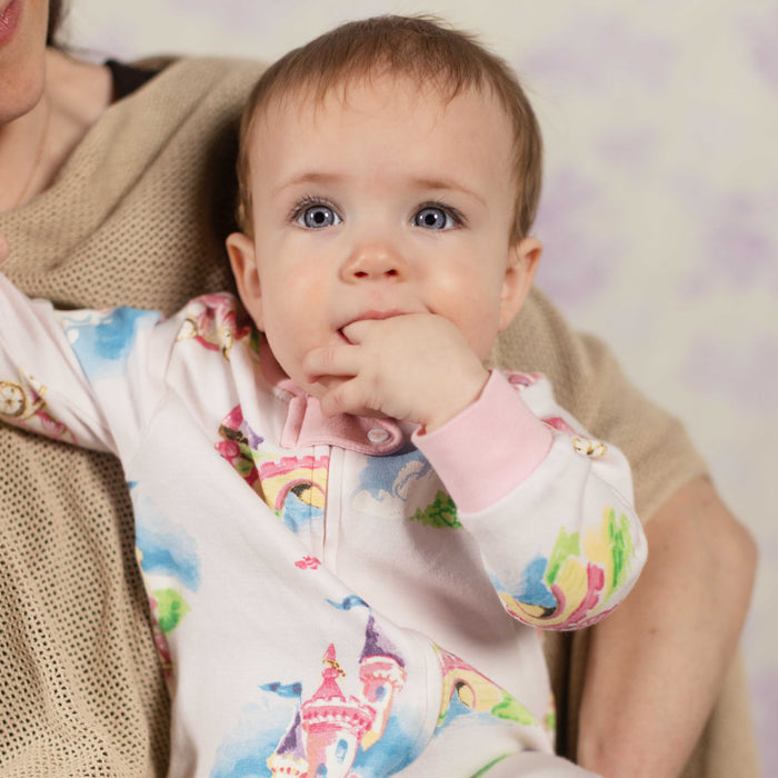 Baby in cream sleep & play with pink collar and pastel castle print, long sleeves.