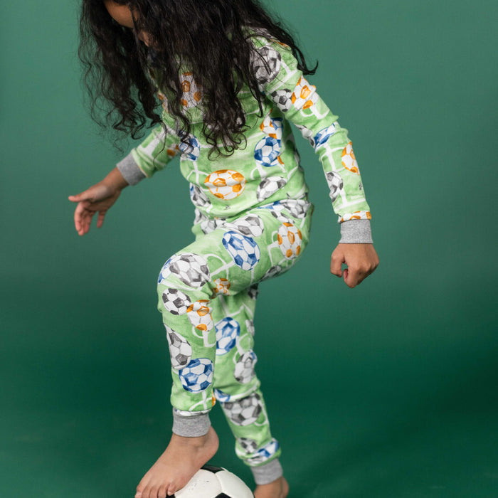 Green soccer-print two-piece pajama set on a child, long sleeves and long pants