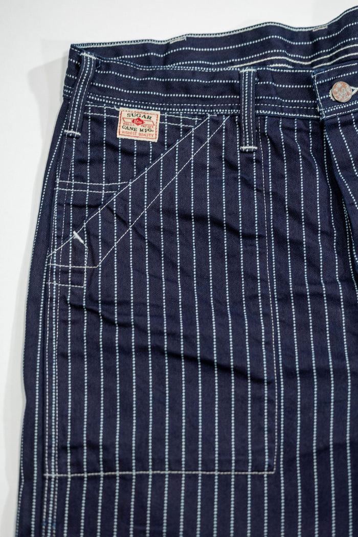 Navy striped fatigue pocket pants close up on full right front pocket with white/red Sugar Cane logo laying flat