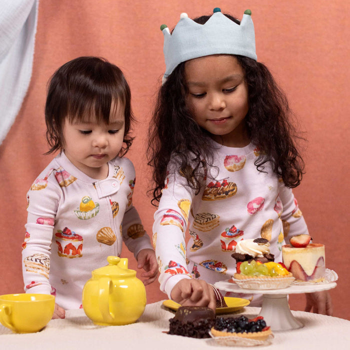 Cream footed pajamas with colorful bakery print worn by two children