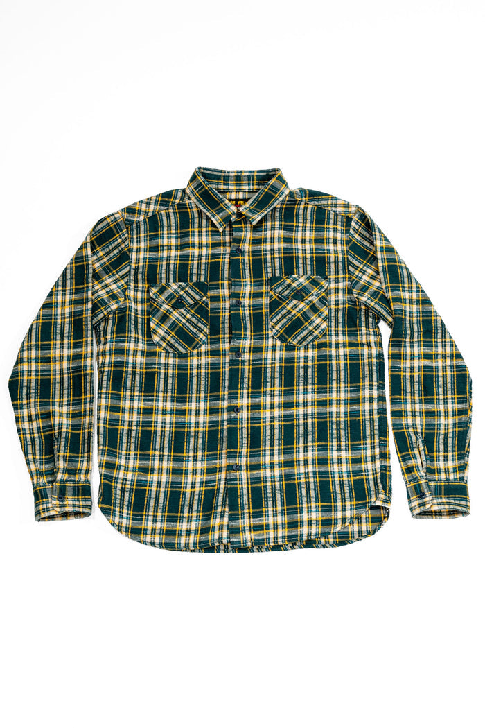 A long-sleeve button-up flannel shirt with a green, yellow, and white plaid pattern, featuring two chest pockets, laid flat on a white background. 
UES 502655 Slubby Flannel Shirt - Green