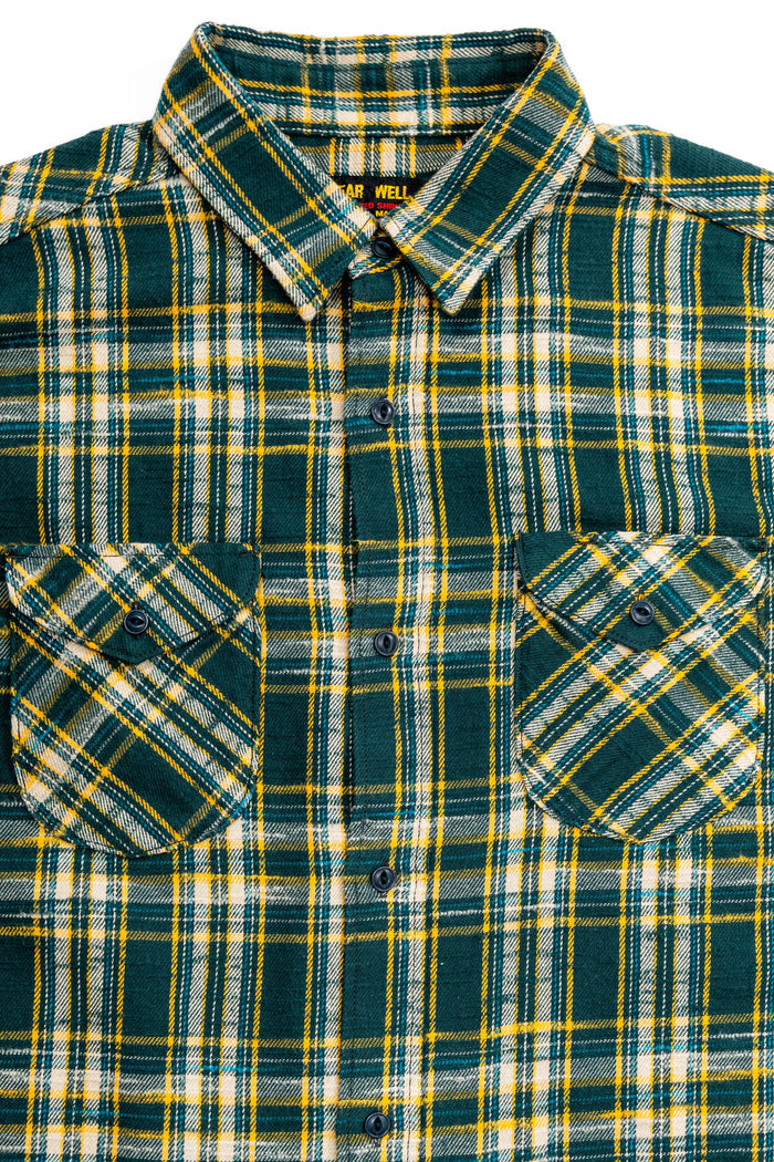 A close-up of a plaid button-up shirt by Wrangler, featuring a dark green base with yellow and white stripes, two buttoned chest pockets, and a collar.

UES 502655 Slubby Flannel Shirt - Green