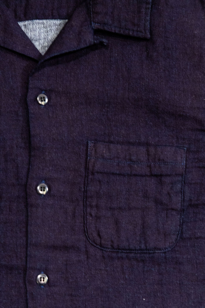 UES Herringbone Double Gauze Short Sleeve Shirt - Indigo: Close-up of a dark indigo or navy textured button-up shirt with a chest pocket and silver buttons.