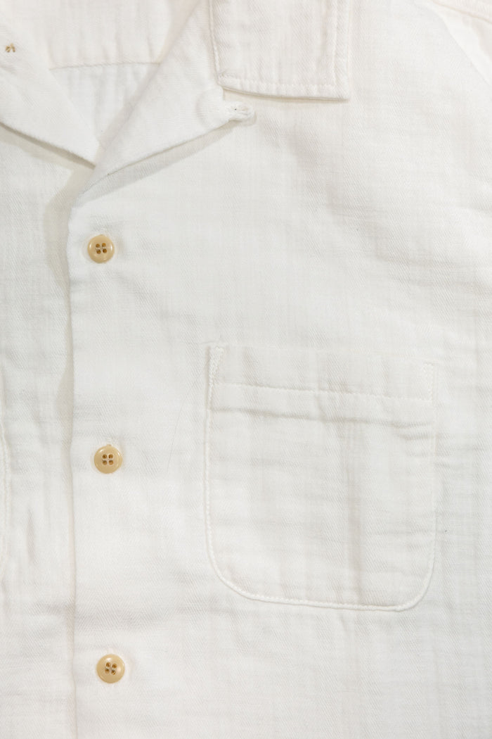 UES Herringbone Double Gauze Short Sleeve Shirt - White: Close-up of a white textured linen shirt showing the collar, three light wood buttons, and a chest pocket.