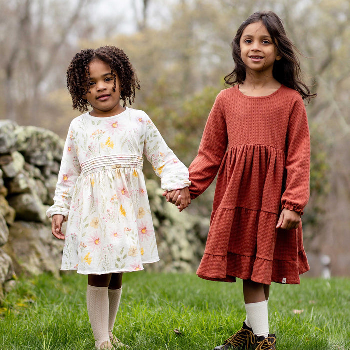 White floral long-sleeve dress with tiered gathered skirt, worn outdoors