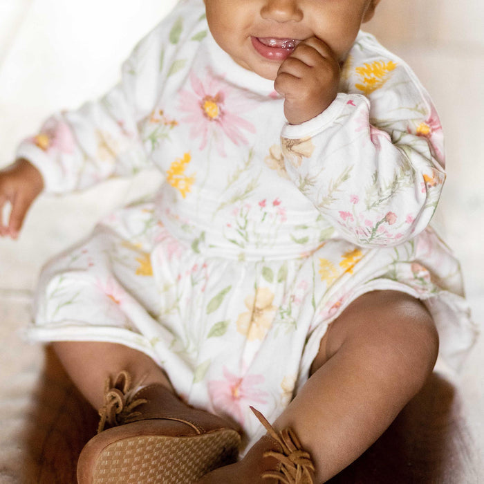 White long-sleeve floral dress with gathered waist, worn by toddler